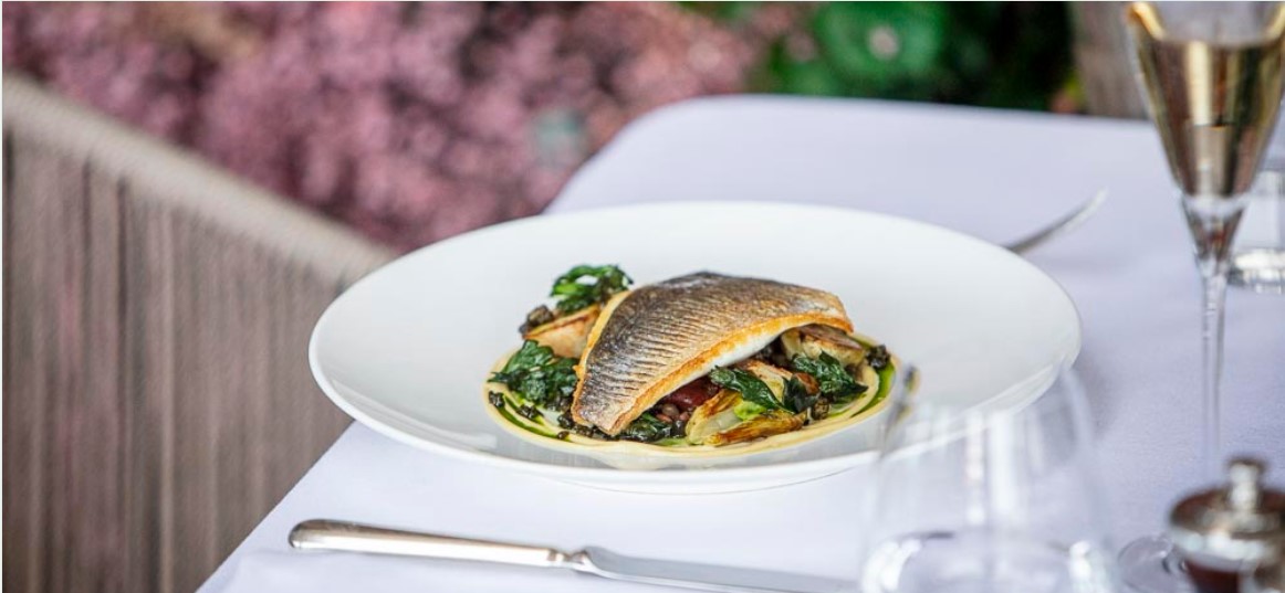 a seafood dish on a set table with cutlery and a glass of wine