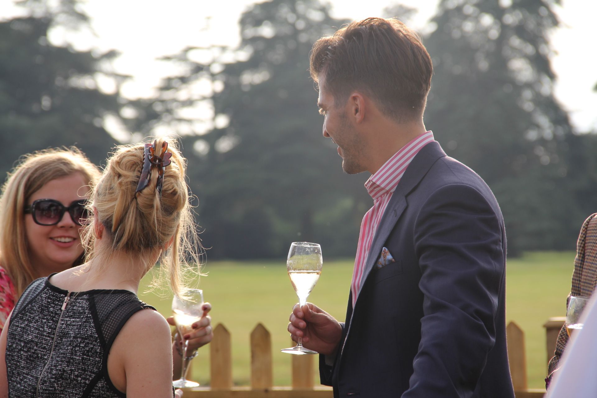 a man holding a glass of wine talking to two women