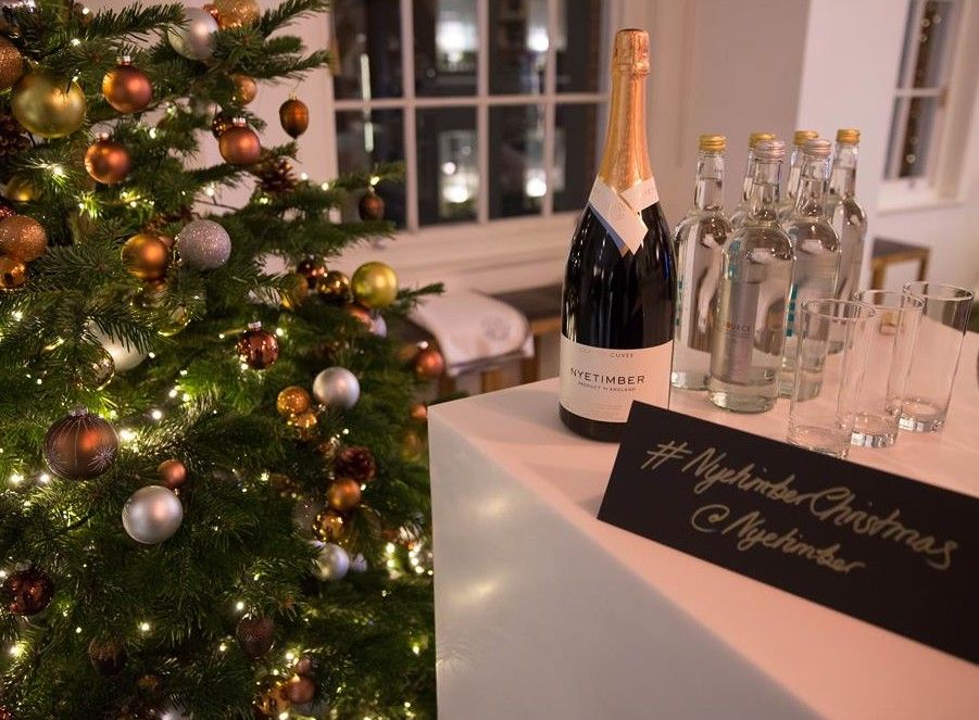 wine, water and glasses next to a decorated christmas tree