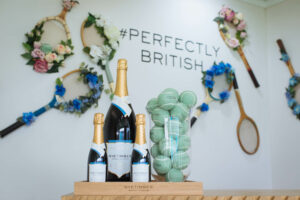 wine bottles next to floral decorated tennis racket and tennis balls