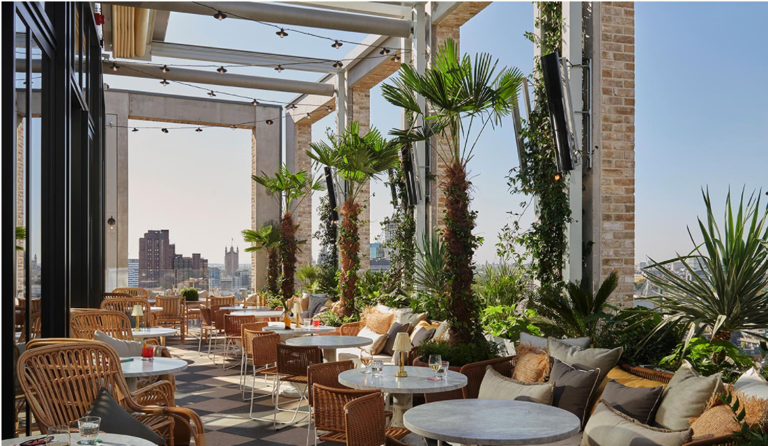a high rise restaurant terrace complete with tables and chairs, and decorated with tropical plants and lights