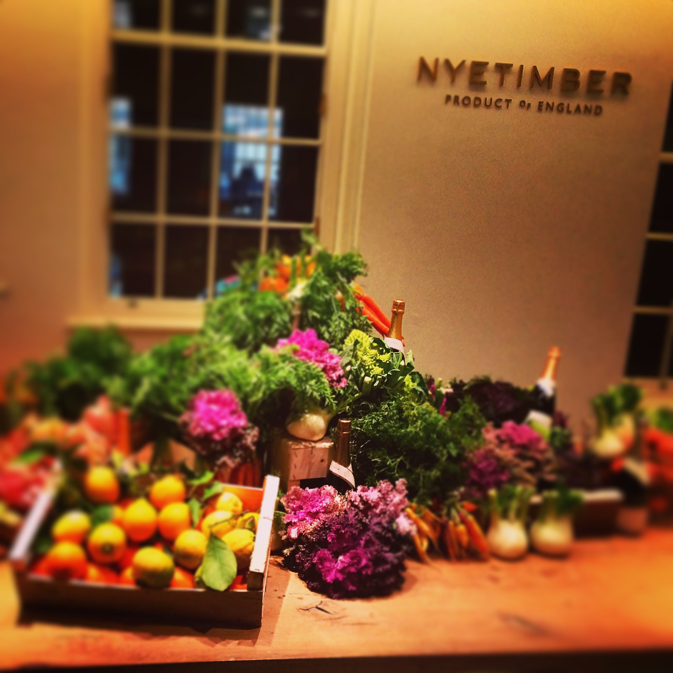 a presentation of fruit of vegetables surrounded by bouquets of pink and purple flowers