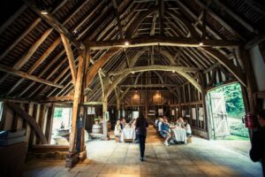 a group of people having a meal in a outdoor wooden barn with exposed beams