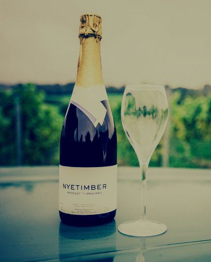 a bottle of Nyetimber wine and empty wine glass on a garden table